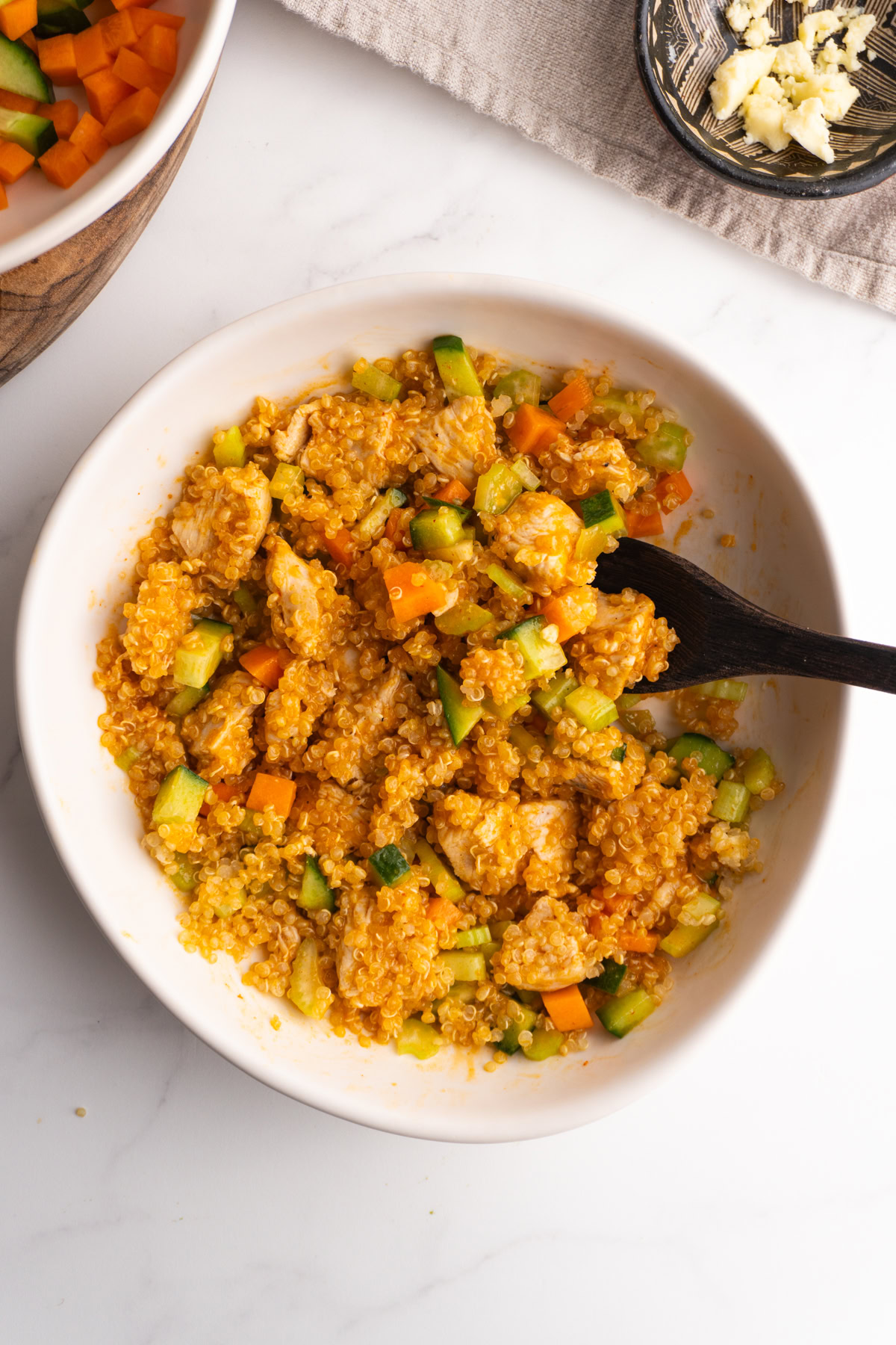 Buffalo chicken bowl with everything mixed up with a small wooden spoon.