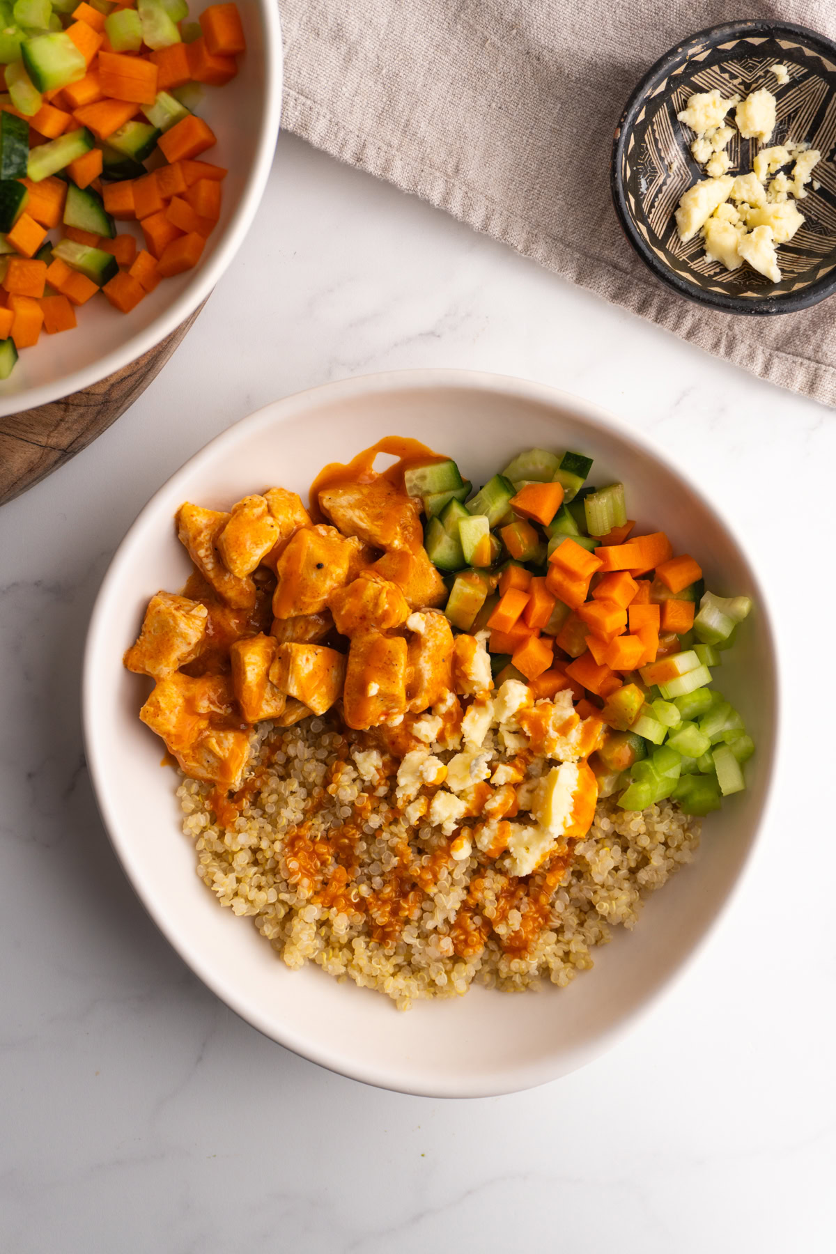 Buffalo chicken served with quinoa, veggies and blue cheese in a bowl.