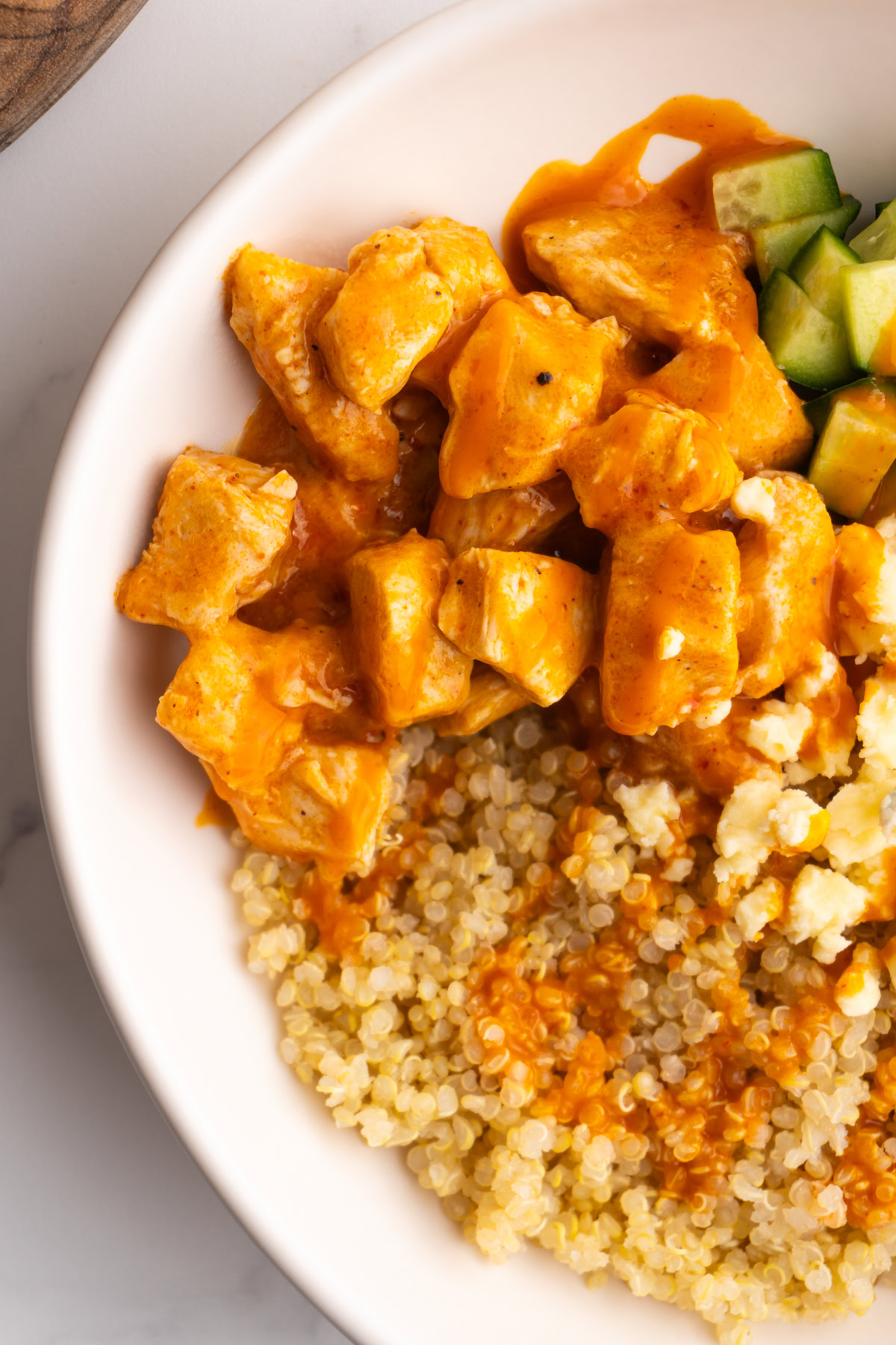 Close up of saucy buffalo chicken and quinoa in a bowl.