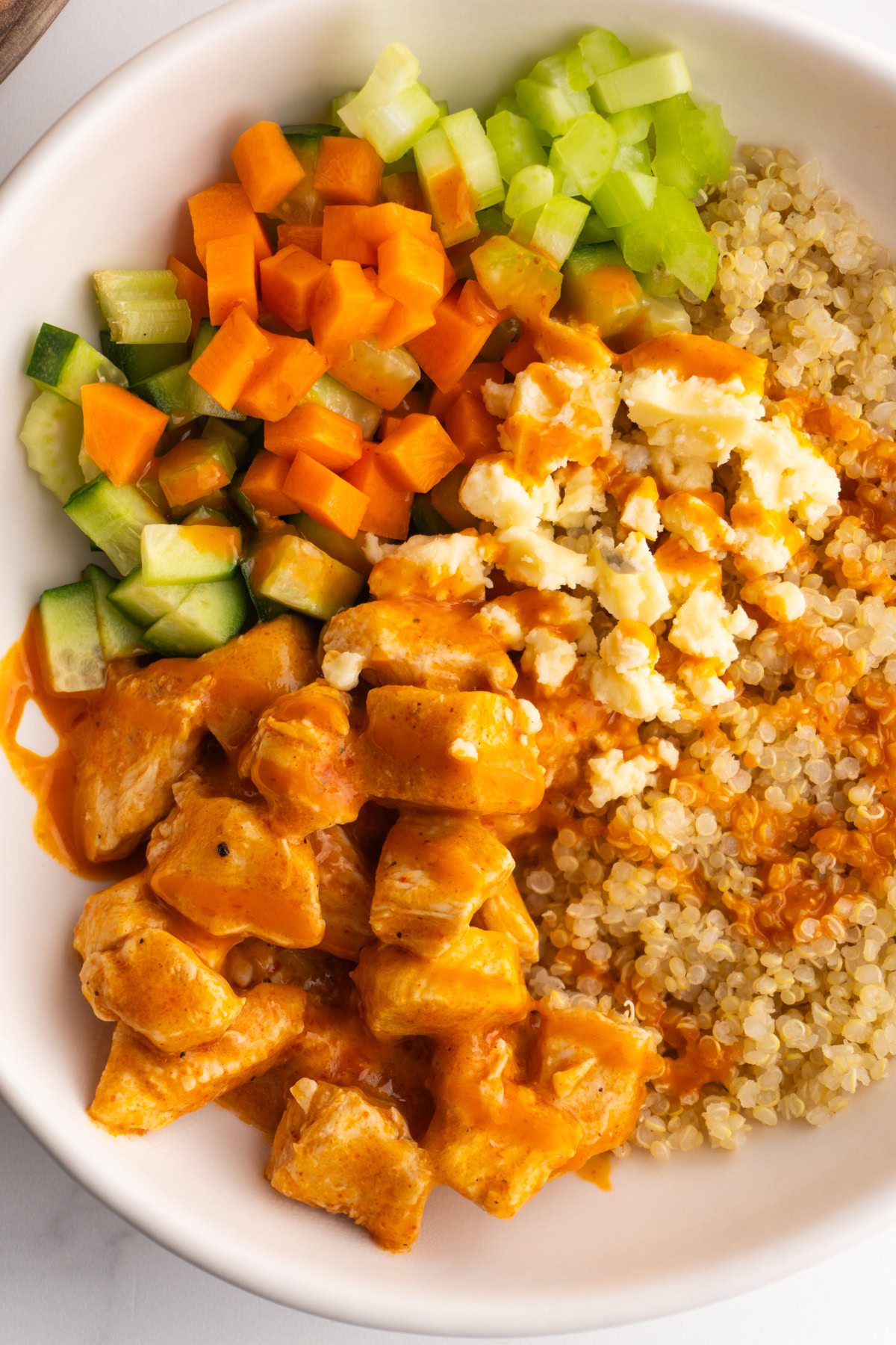 Buffalo chicken bowl with chicken, quinoa, blue cheese, and veggies.