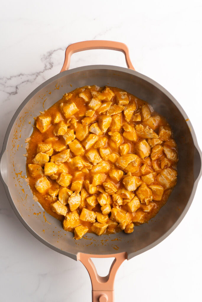 Chicken cooking in buffalo sauce marinade.