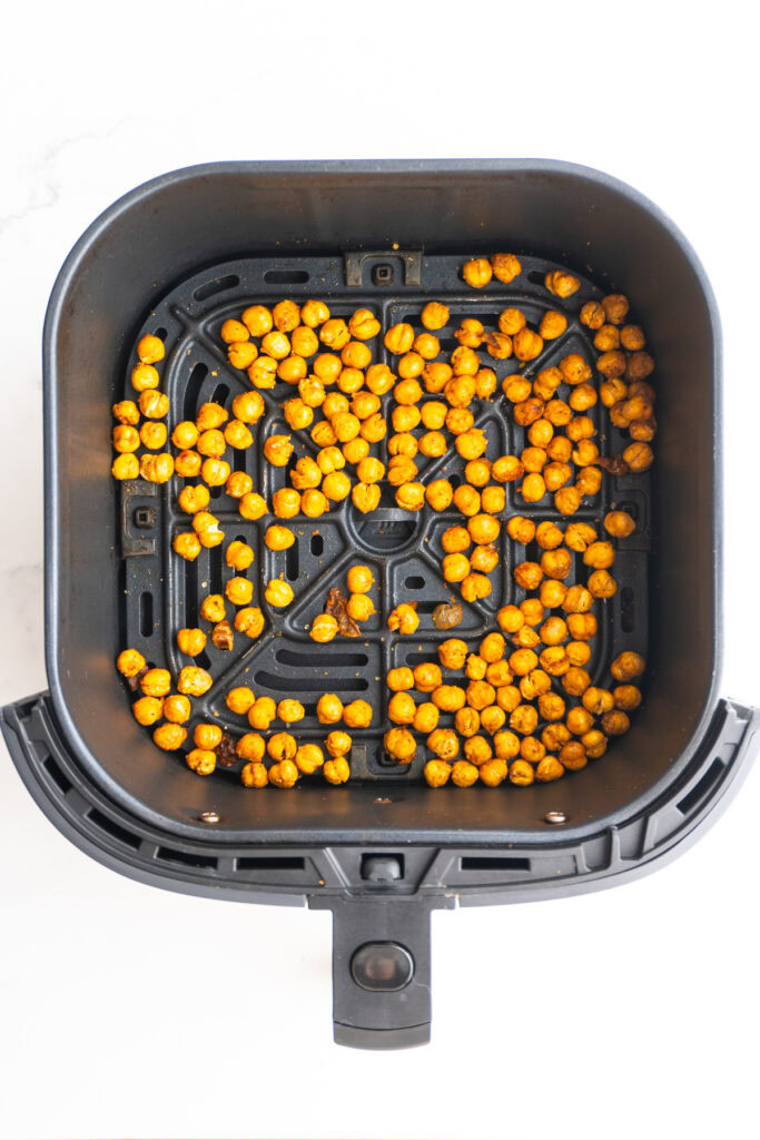 Crispy chickpeas in the air fryer basket after cooking.