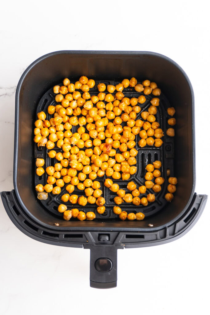 Seasoned chickpeas added to the air fryer basket.