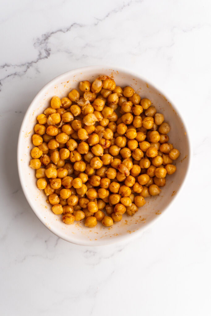 Chickpeas in a white bowl after mixed with olive oil and spices.
