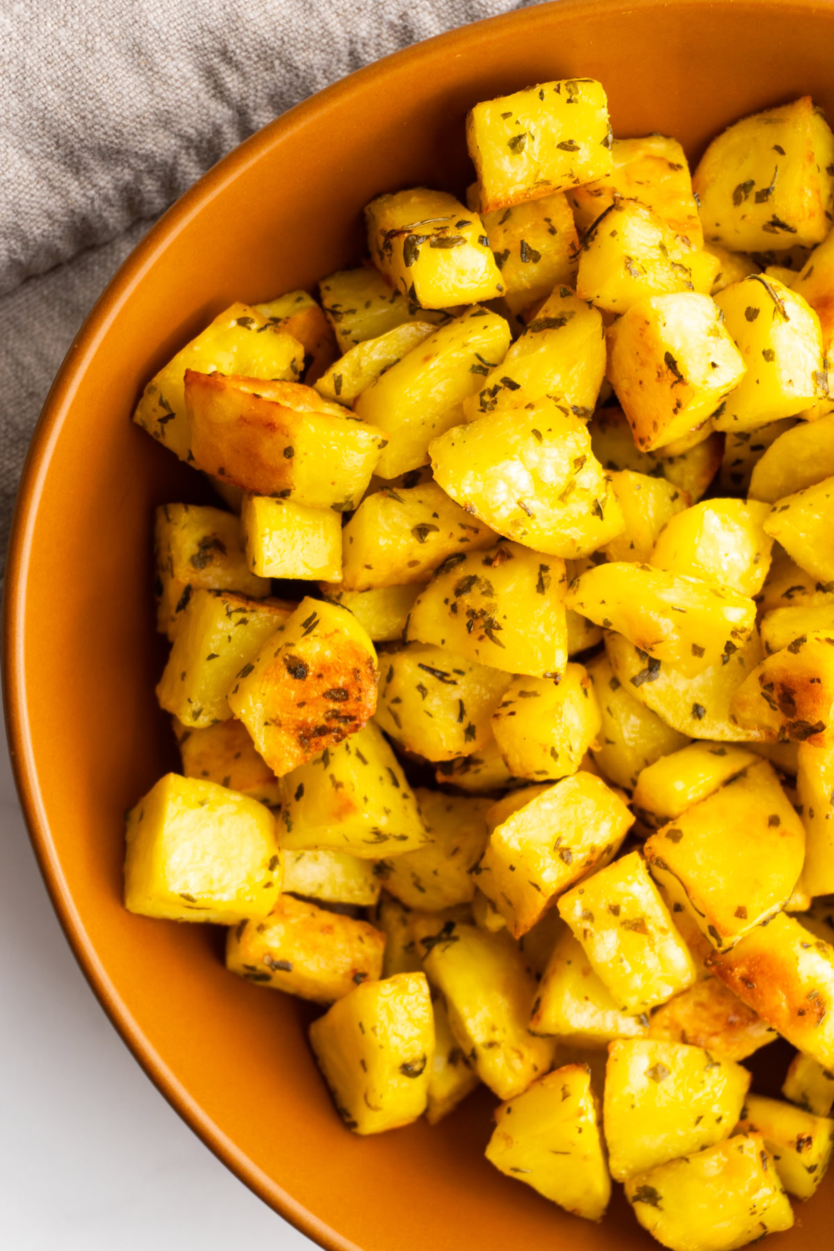 Close up of crispy roasted potatoes in a bowl.