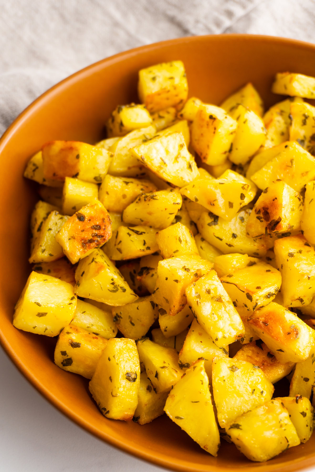 Close up of crispy roasted potatoes in a bowl.
