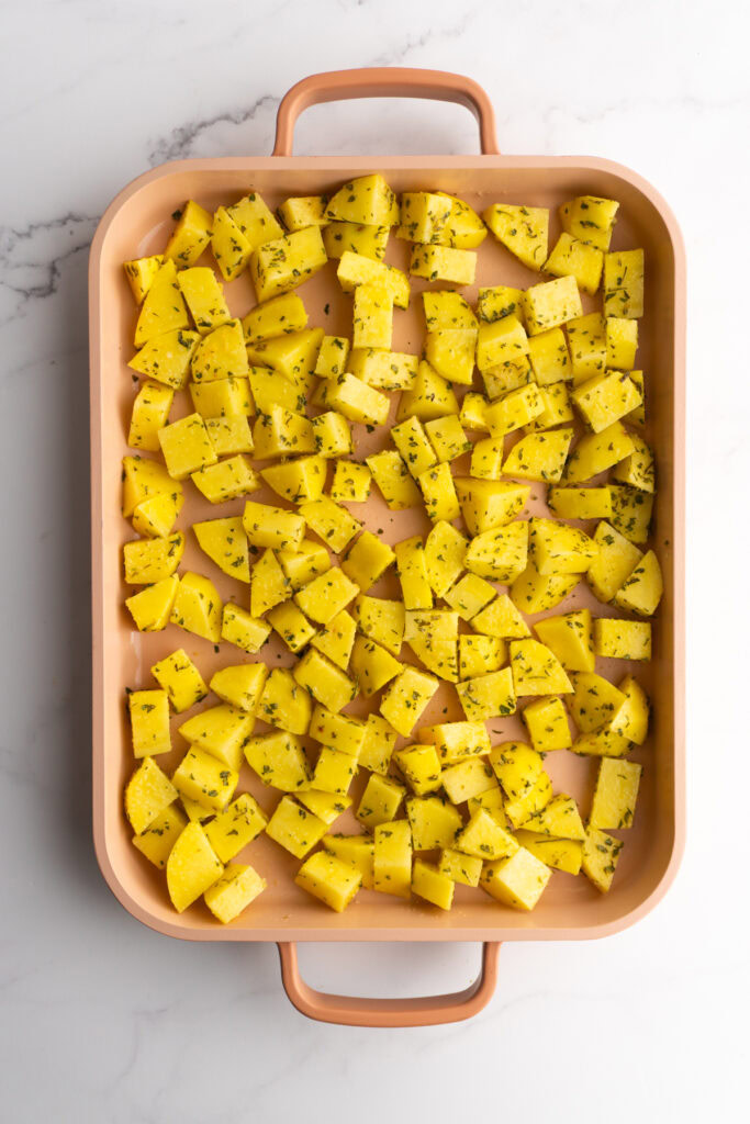 Diced and seasoned potatoes on a sheet pan.