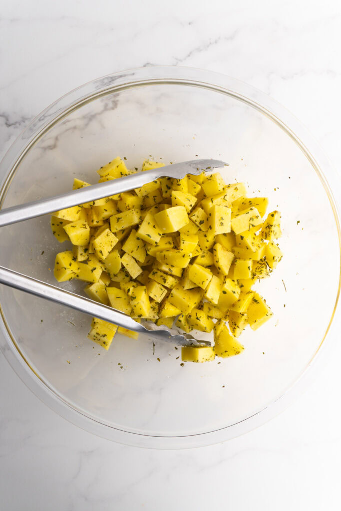 Seasoned and diced potatoes in a mixing bowl.