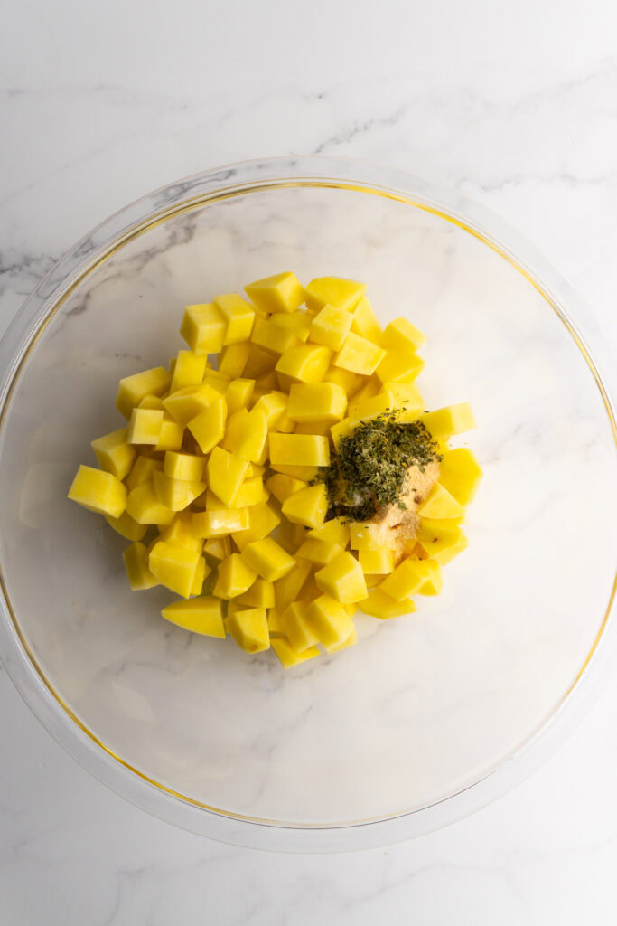 Diced potatoes in a bowl before being mixed with seasonings.
