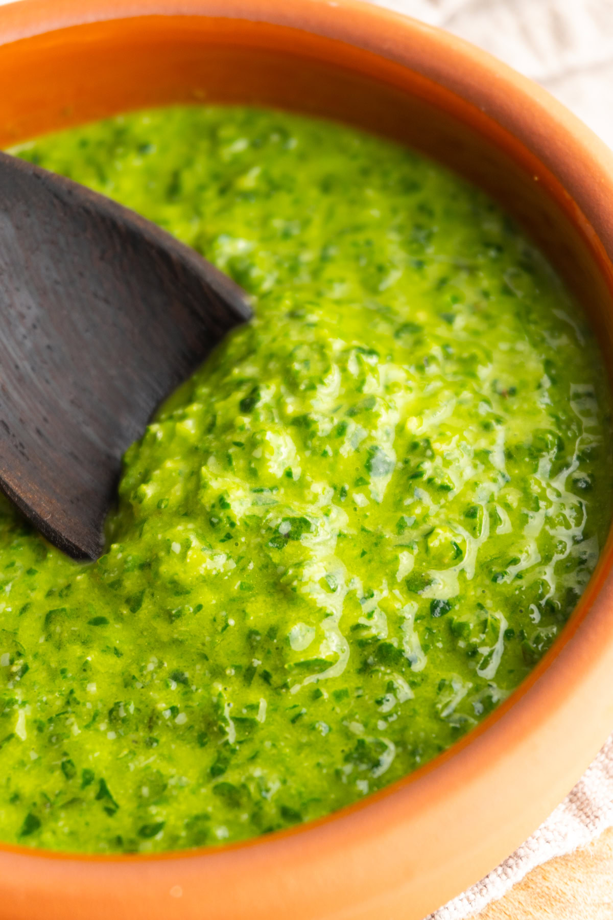 Close up of fresh pesto sauce in a bowl with a spoon.