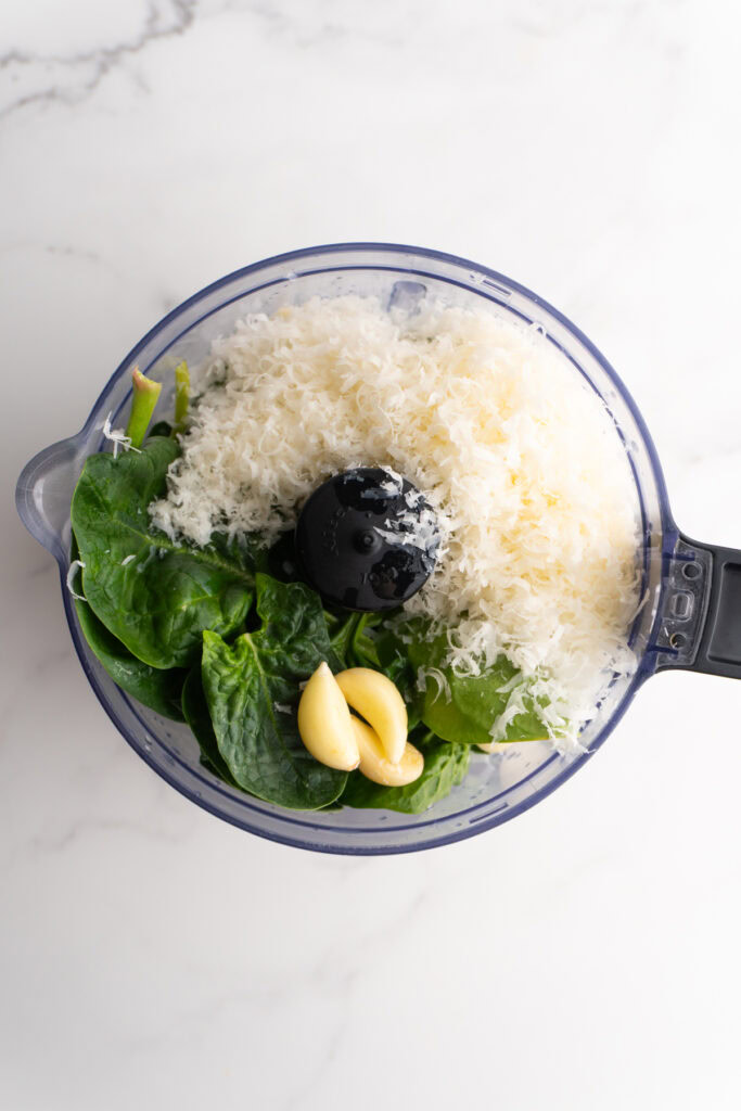 Ingredients for homemade fresh pesto sauce in the food processor before blending.