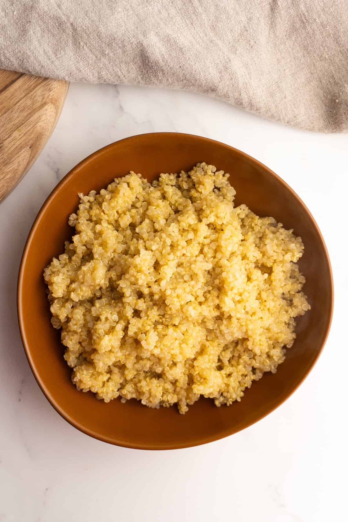 Quinoa in a clay bowl on a white background.