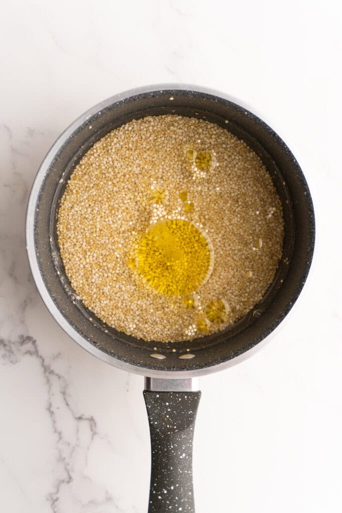 Quinoa in a saucepan with water and olive oil.