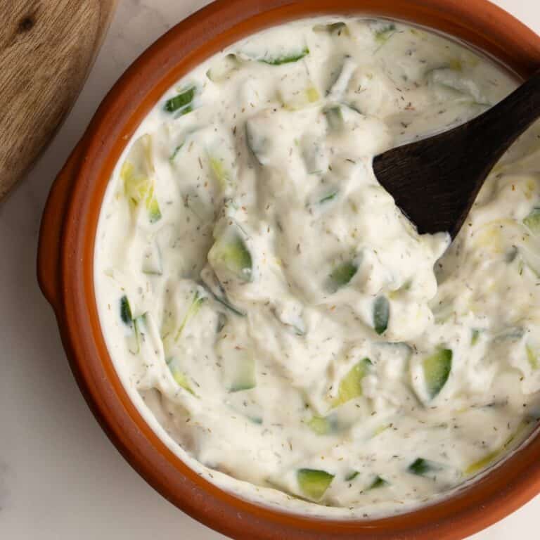 Tzatziki sauce in a clay bowl with a small wooden spoon.