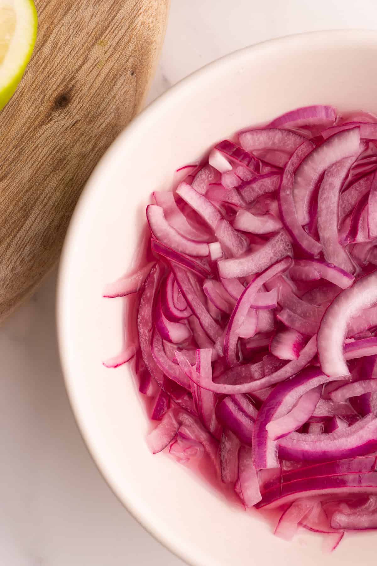 Close up of lime pickled onions in a white bowl.