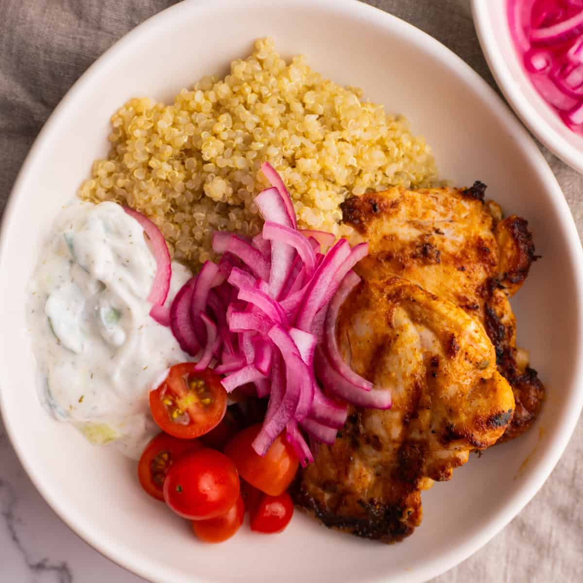 Mediterranean chicken quinoa bowl served in a white bowl.