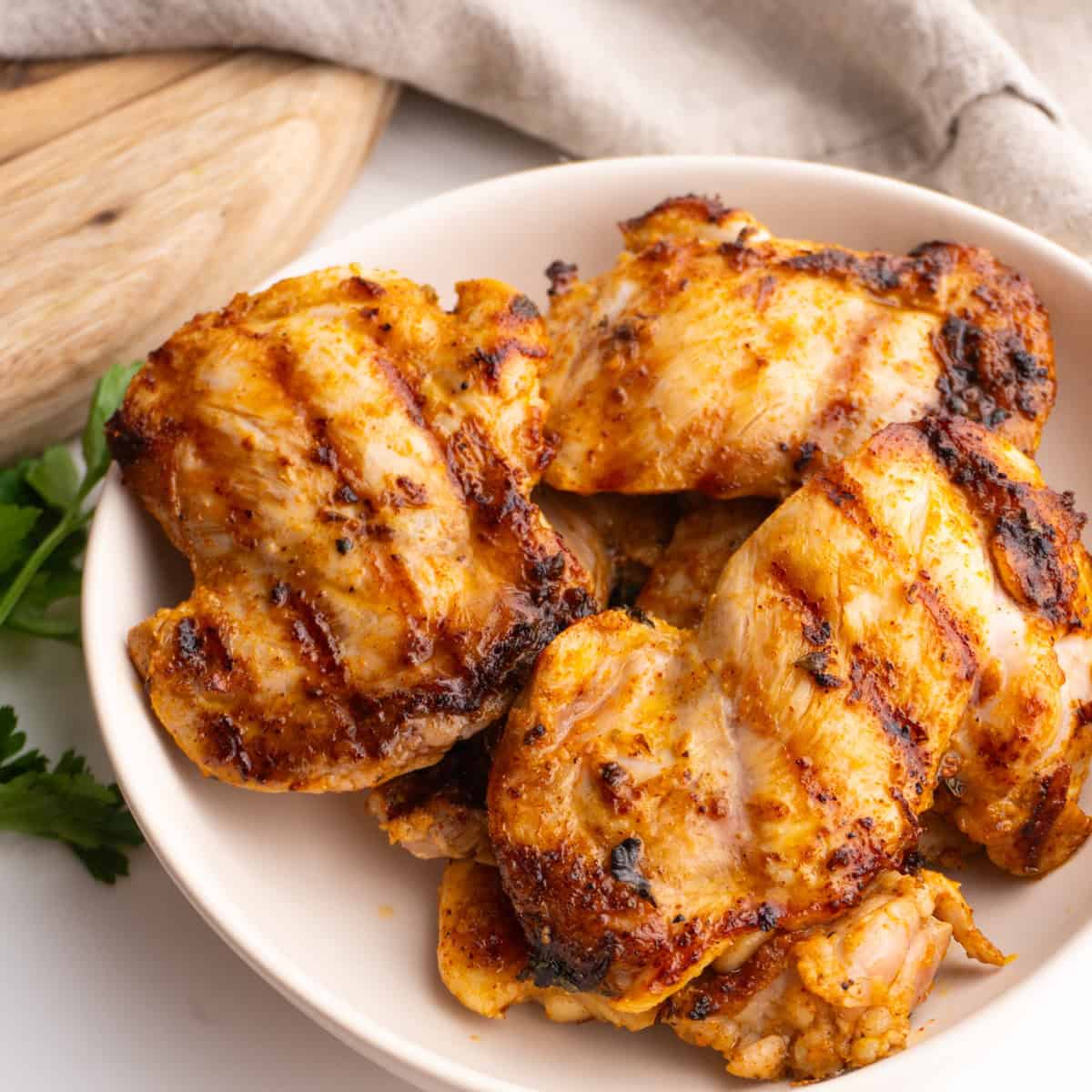 Mediterranean chicken thighs served in a white bowl.