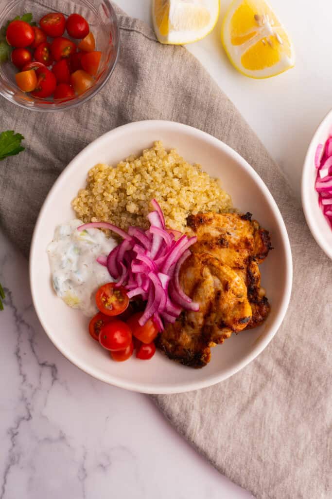 Overhead shot of a mediterranean chicken quinoa bowl served in a white bowl.
