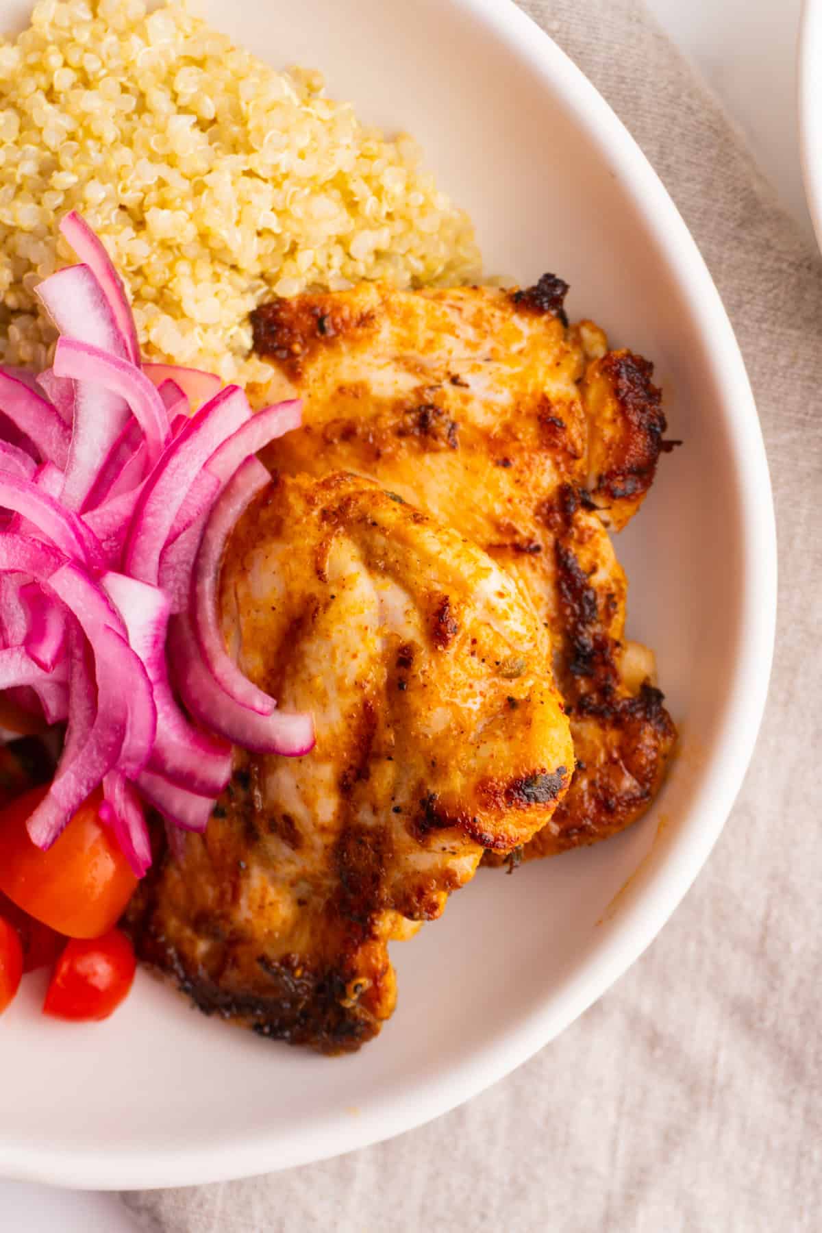 Chicken thighs in a mediterranean chicken quinoa bowl.