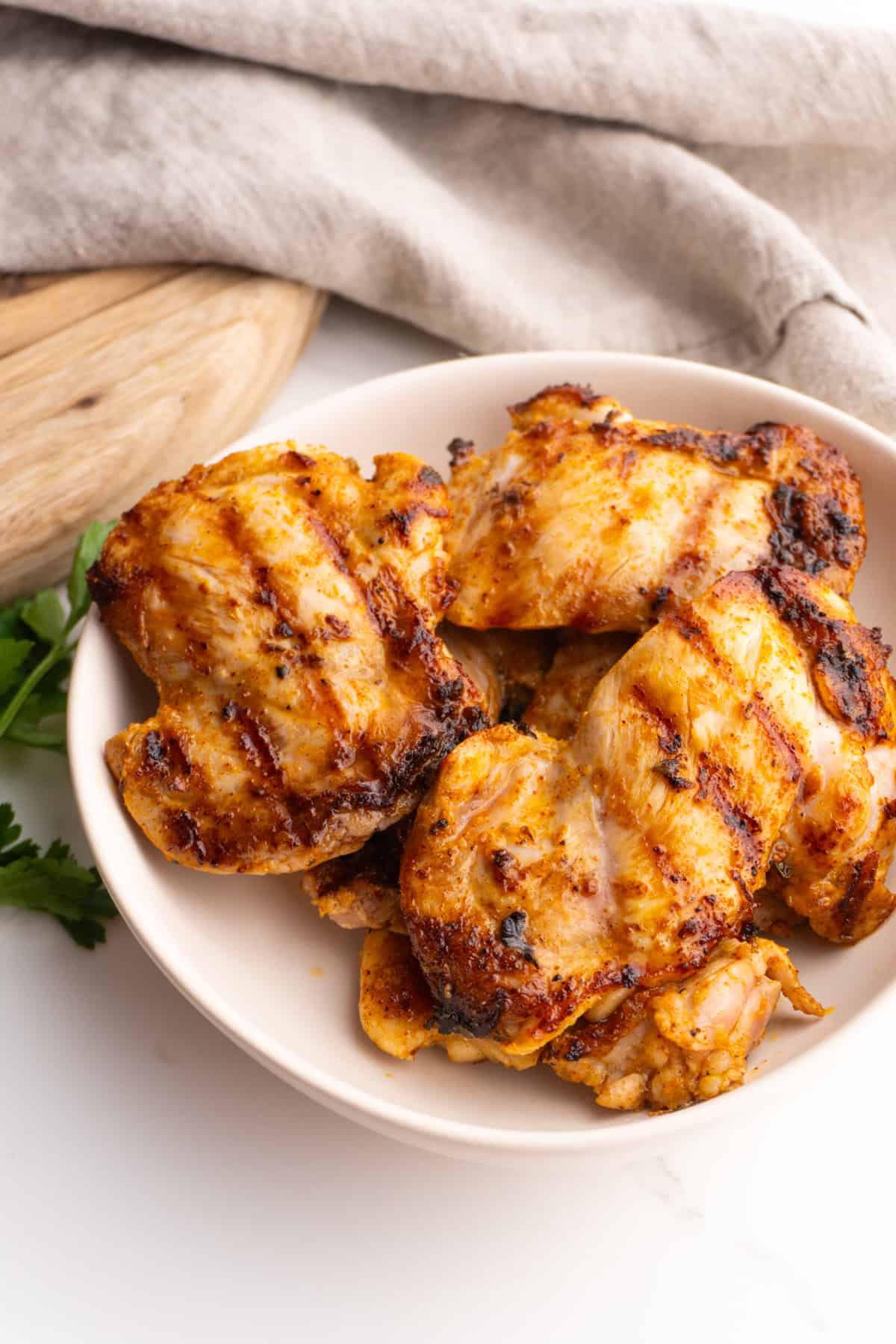 Mediterranean chicken thighs served in a white bowl.