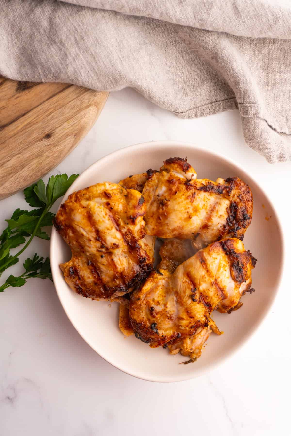 Overhead shot of mediterranean chicken thighs with grill marks on them.