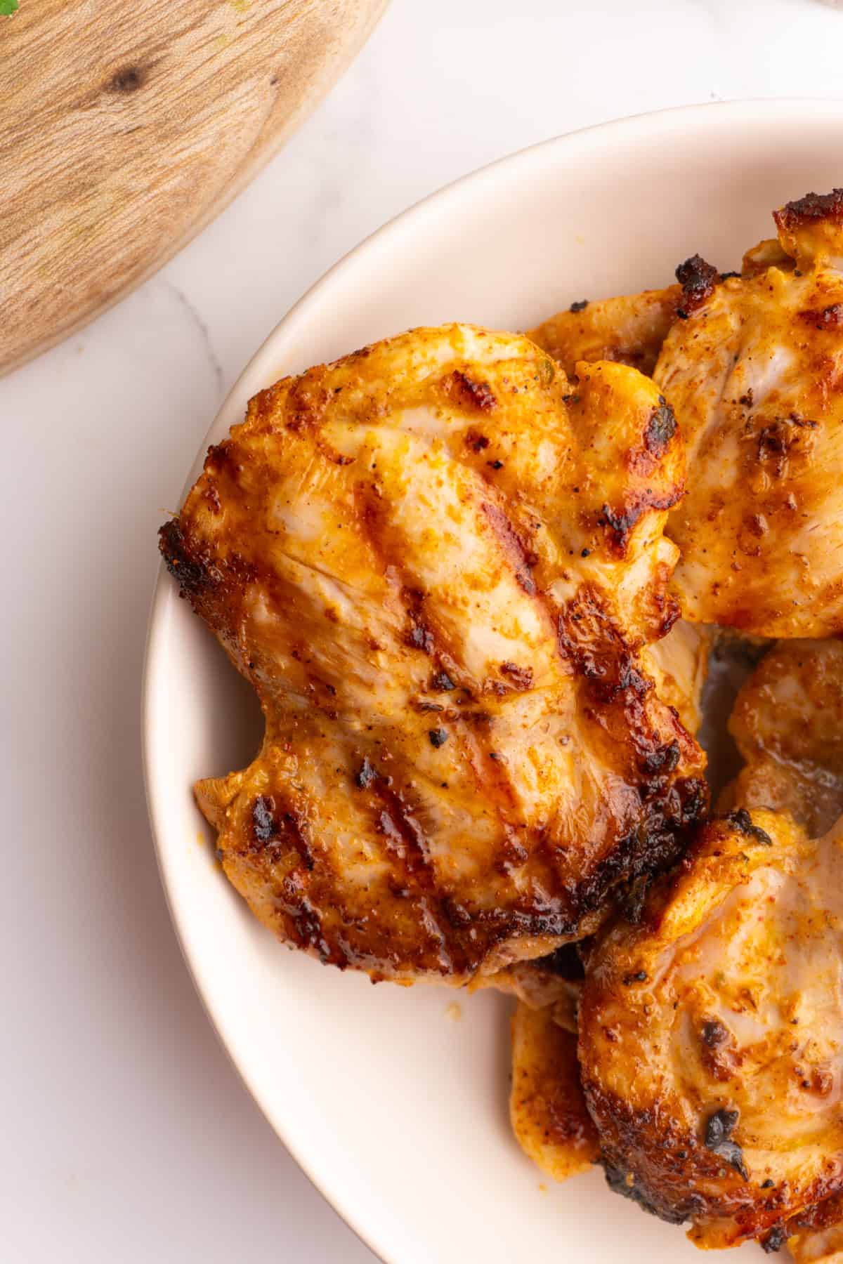 Close up of Mediterranean chicken thighs in a white bowl.