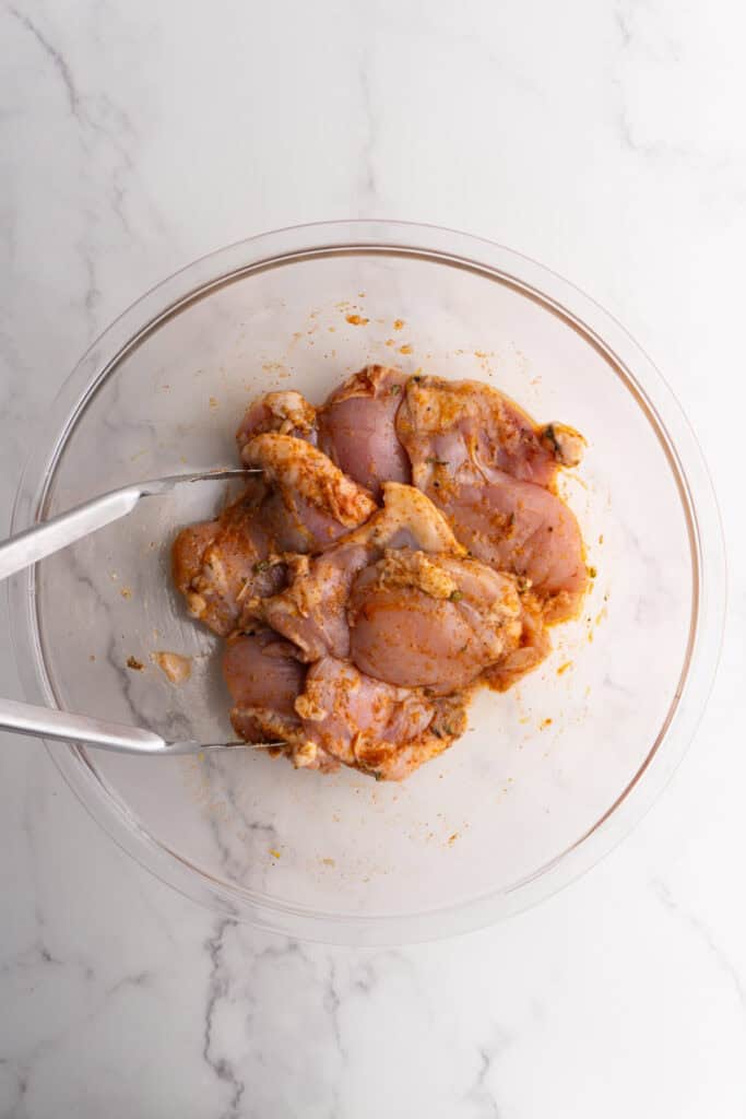 Chicken things in a mixing bowl after being seasoned.