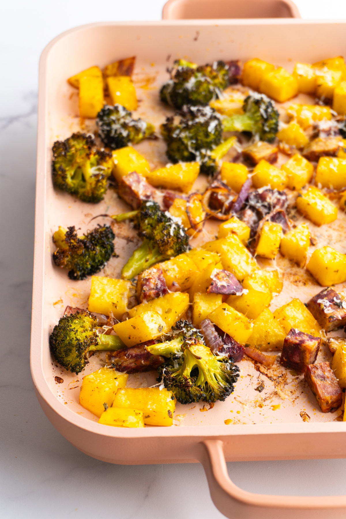 Side view of parmesan roasted vegetables on a sheet pan.