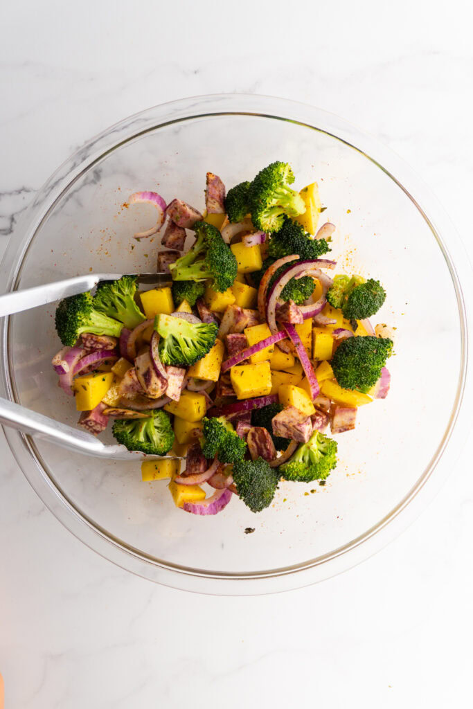 Vegetables in a mixing bowl after being mixed with spices.