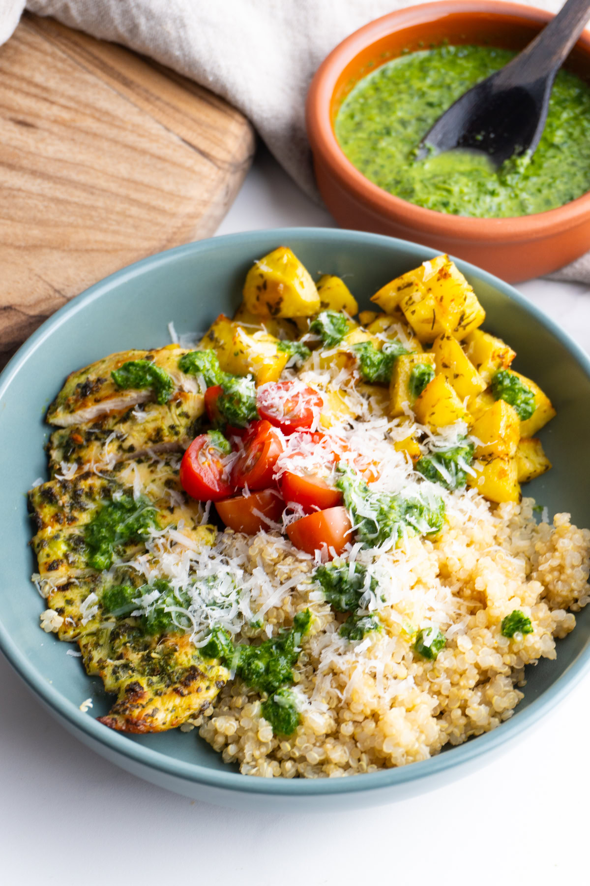 Pesto chicken bowl from the side topped with cherry tomatoes and parmesan.