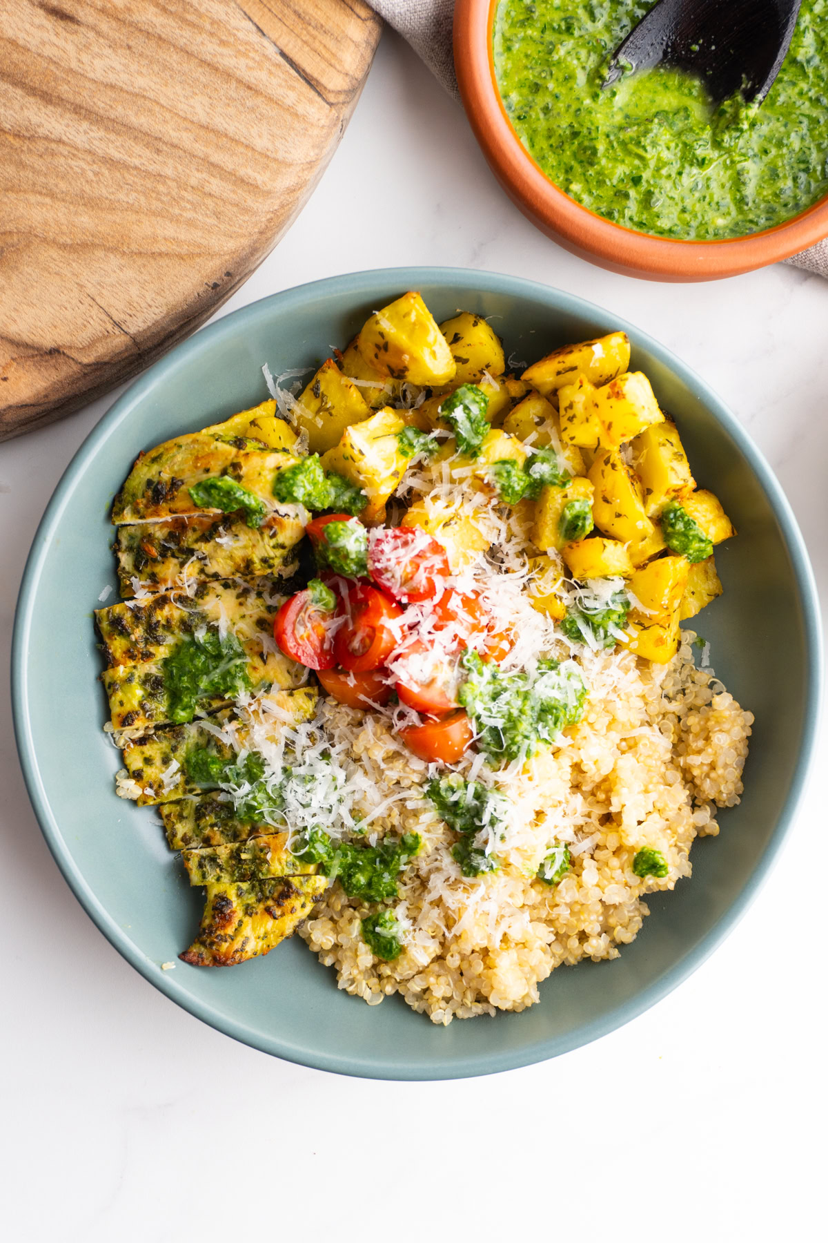 Pesto chicken bowl in a grey bowl with quinoa, potatoes, chicken and tomatoes.