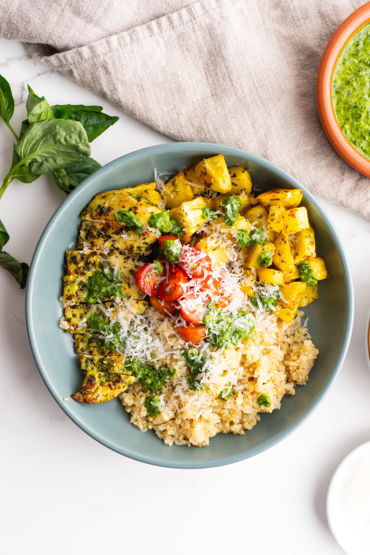 Overhead shot of a pesto chicken bowl with crispy roast potatoes.