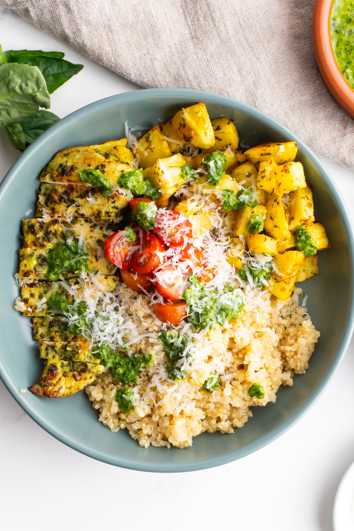 Pesto chicken quinoa bowl in a blue grey bowl.