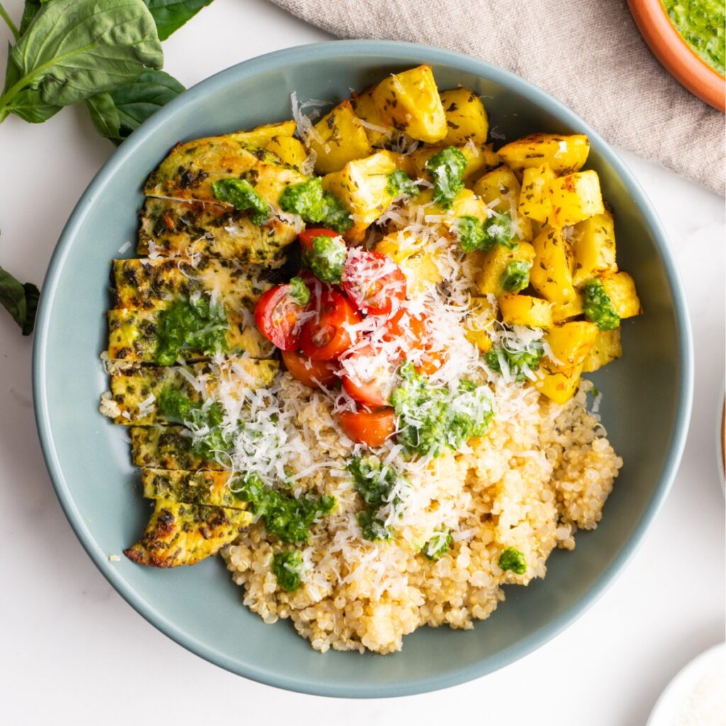 Chicken pesto bowls with fresh tomatoes and parmesan on top.