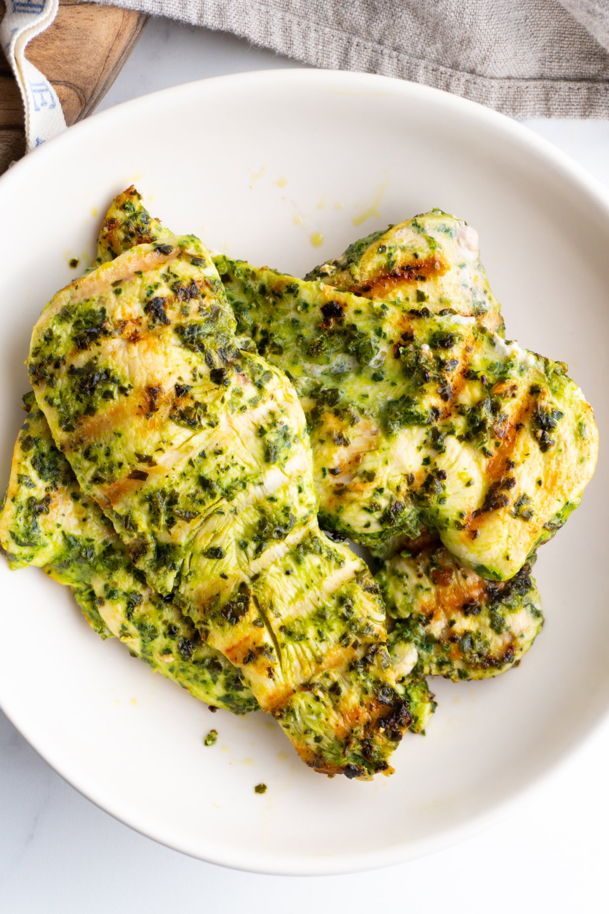 Pesto marinated chicken breast in a white bowl.