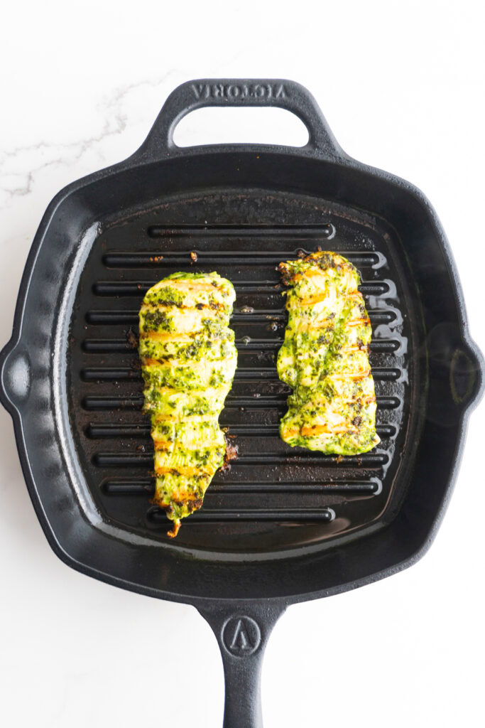 Pesto chicken after being flipped in the cast iron skillet.