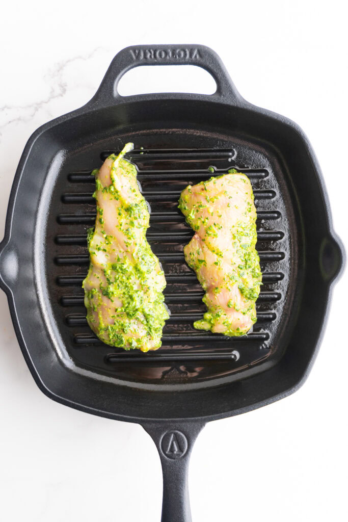 Chicken placed in a cast iron skillet to sear.