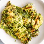 Chicken breasts marinated in pesto served in a bowl.