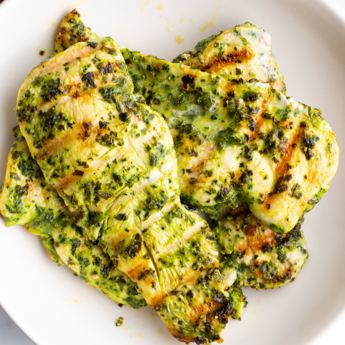 Chicken breasts marinated in pesto served in a bowl.