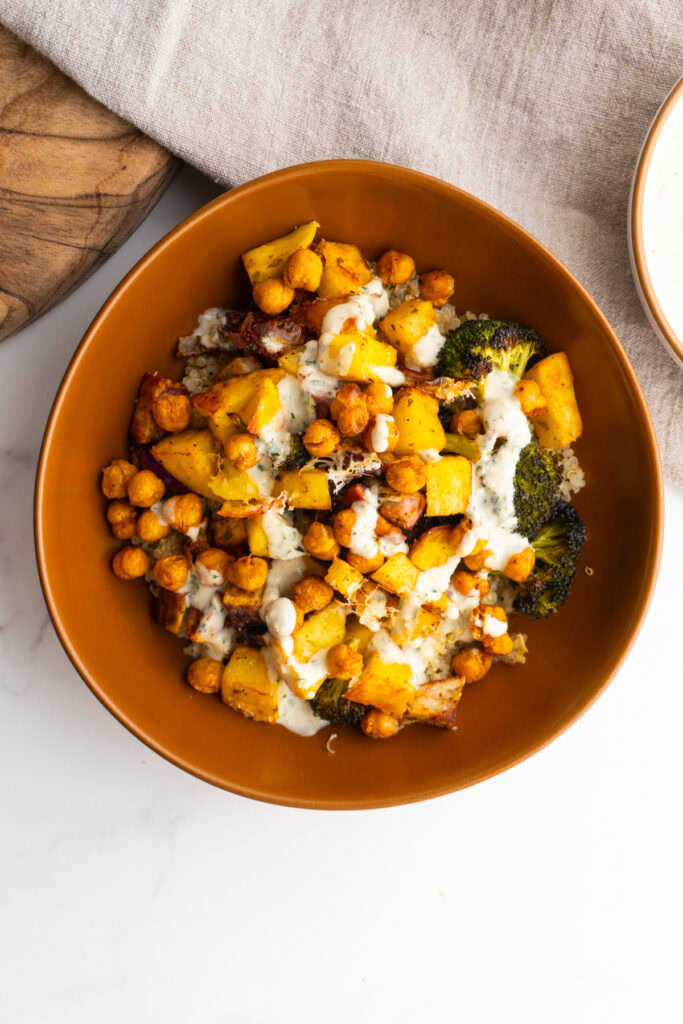 Overhead shot of a roasted veggie bowl with tahini sauce drizzled on top.