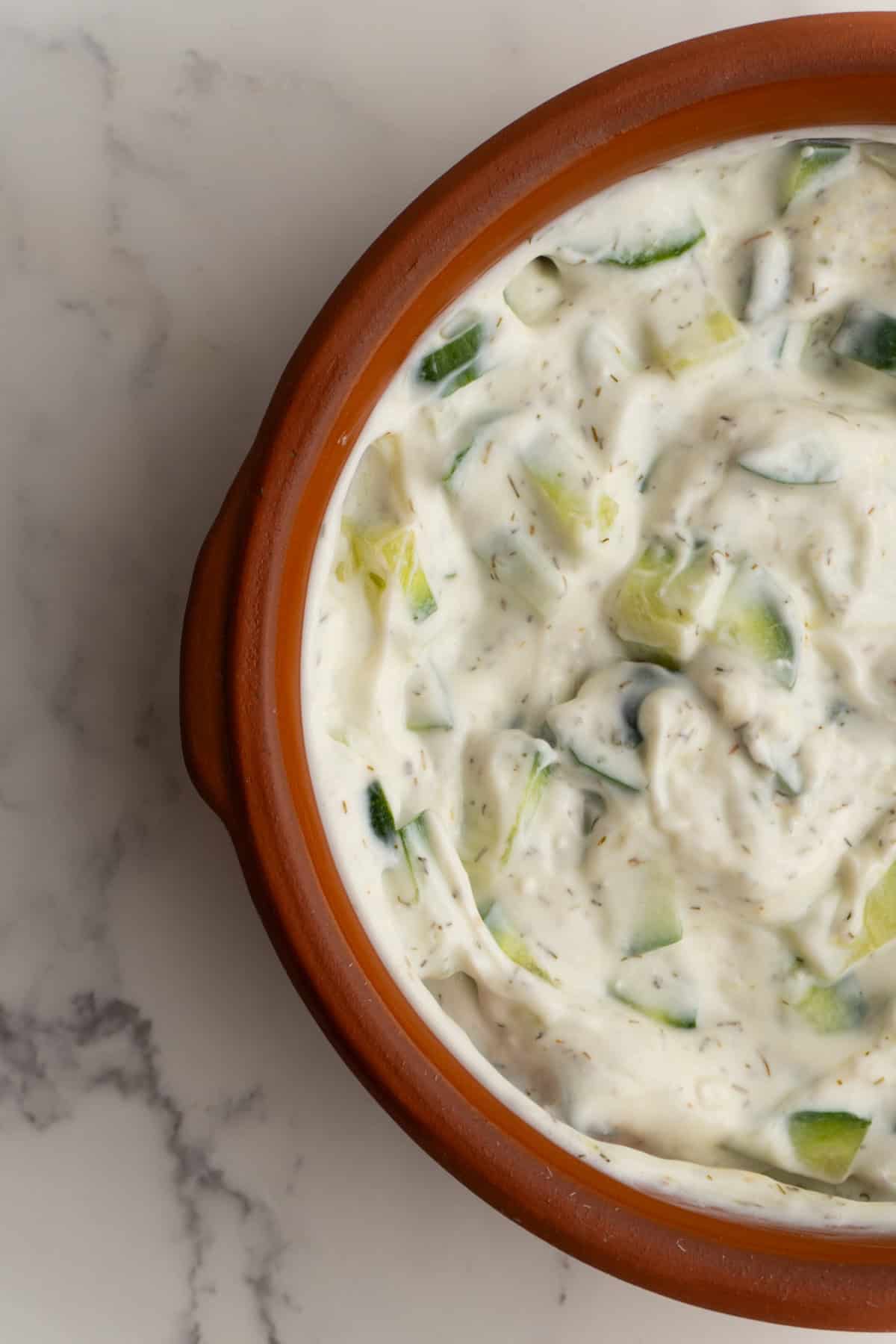 Close up of homemade tzatziki sauce in a clay bowl.