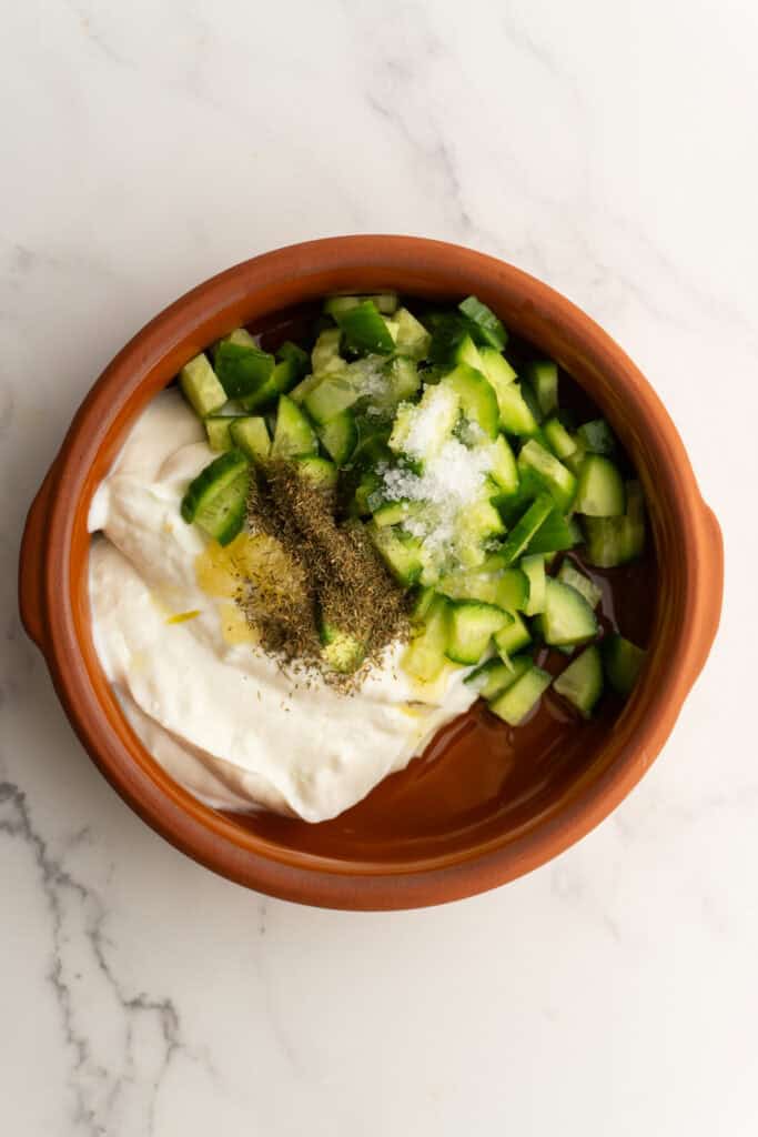 Ingredients for tzatziki sauce in a bowl before mixing.