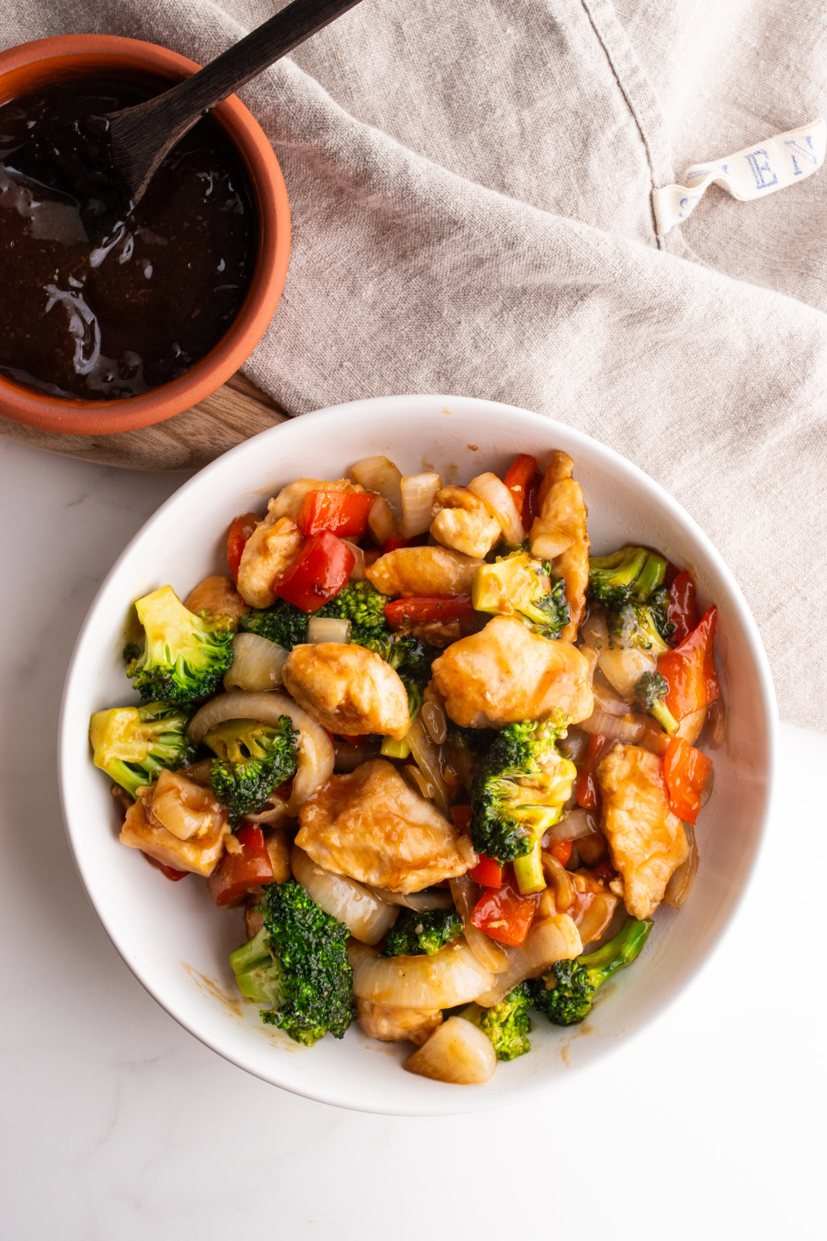Chicken teriyaki stir fry in a bowl next to a small bowl of teriyaki sauce.