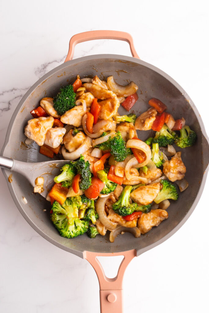 A skillet with chicken, broccoli and red peppers.