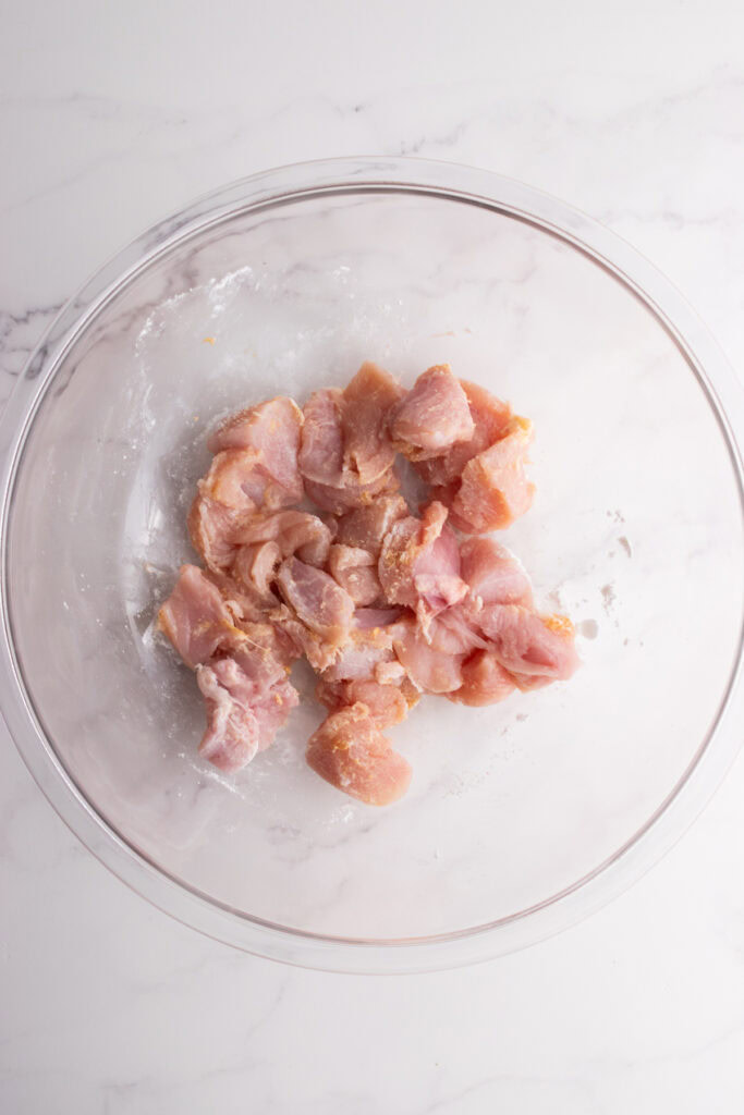 Chicken coated in seasoning and cornstarch in a bowl.
