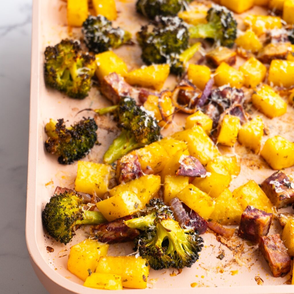 Side view of parmesan roasted vegetables on a roasting pan.