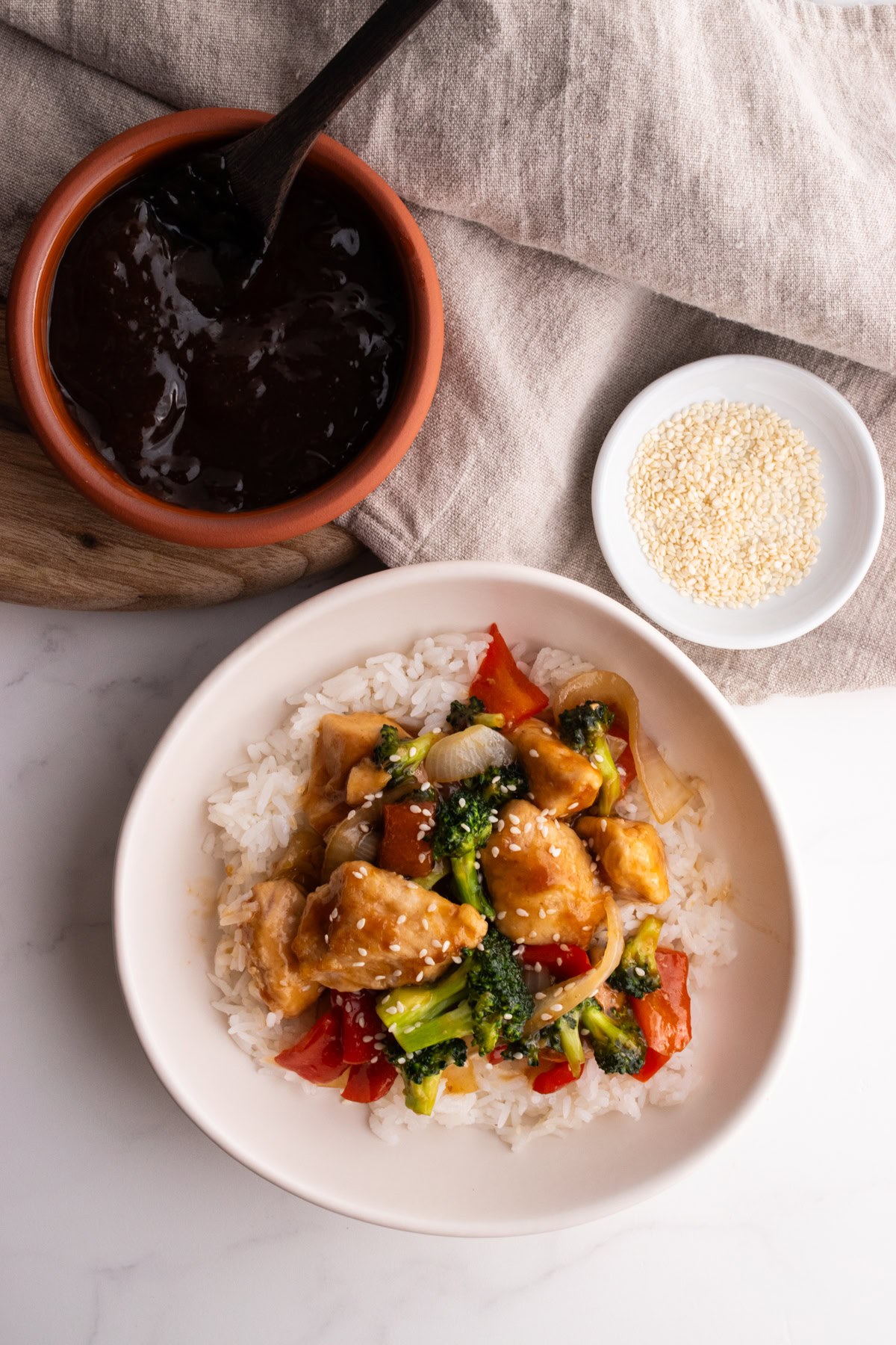 Chicken and veggie stir fry with rice and a side of teriyaki sauce.
