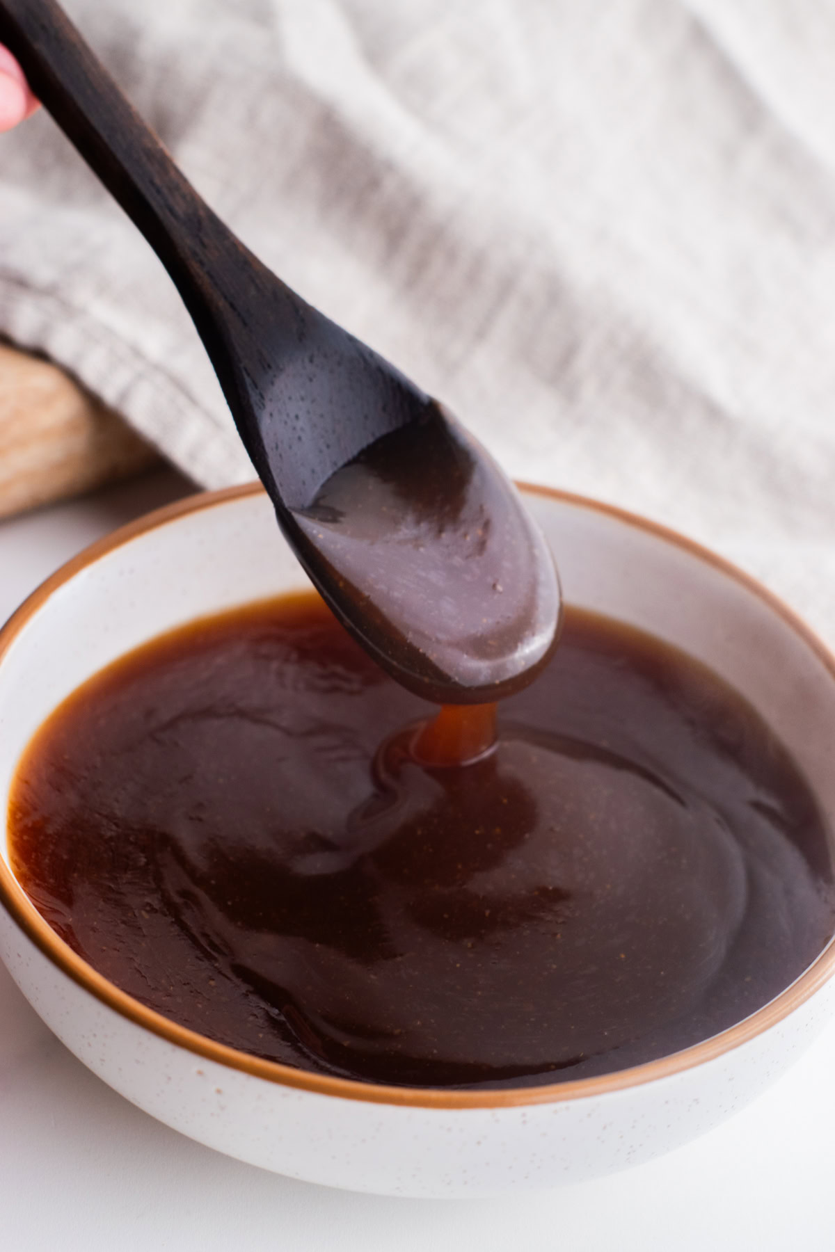 Teriyaki sauce in a bowl with a spoon drizzling some after being dipped.