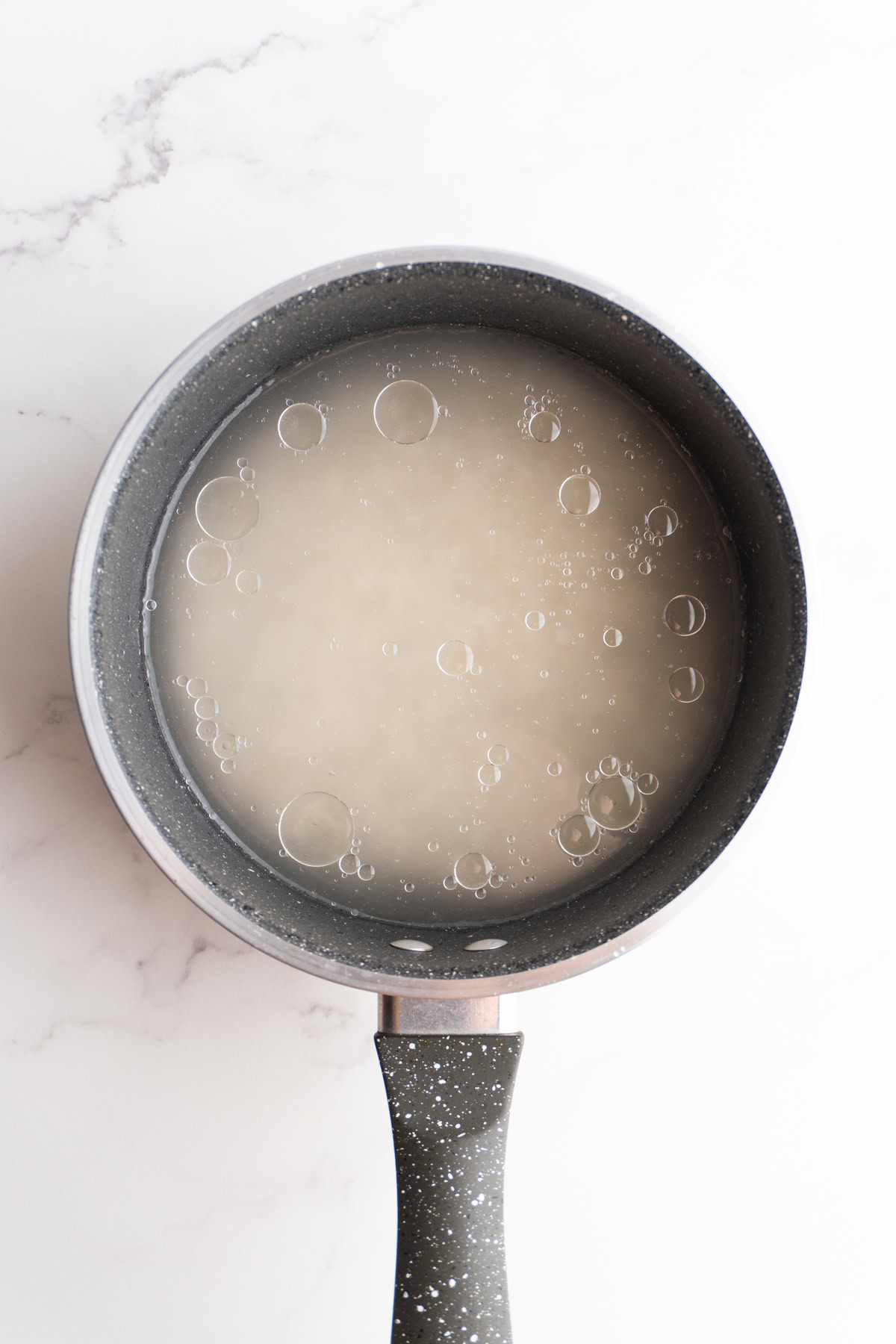 Rice with water and a little oil in a saucepan.