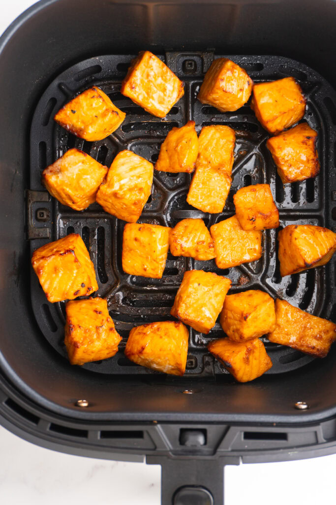 Air fried salmon bites in the air fryer basket after cooking.